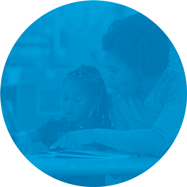 Adult helping child read a book.