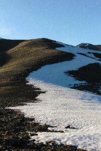 Snowy path winding through barren mountain landscape.