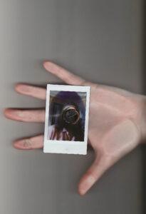 Hand holds polaroid with blurred portrait inside