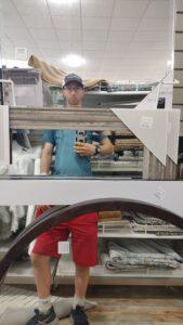 Person taking mirror selfie in home goods store.