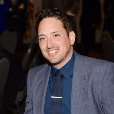 Smiling person at a formal event in suit.