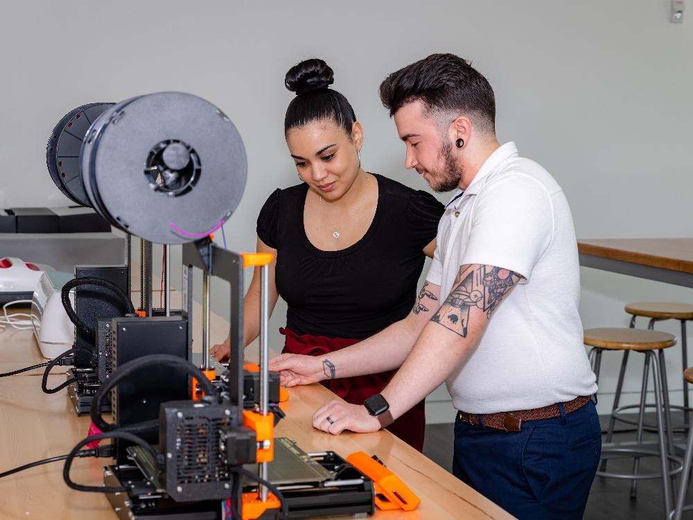 Two people working with a 3D printer.