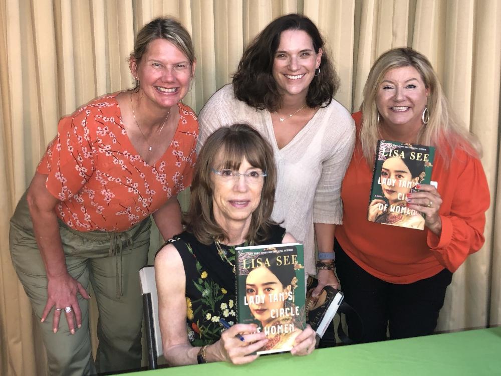 Four women holding 'Lady Tan's Circle of Women' book.
