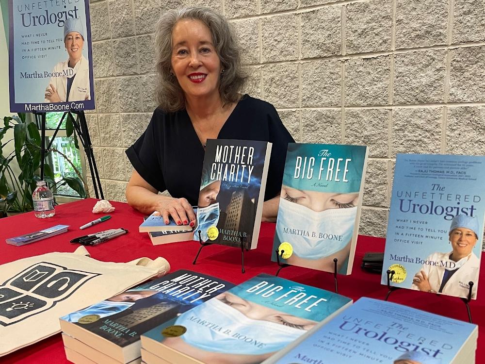 Author signing books at event table display.