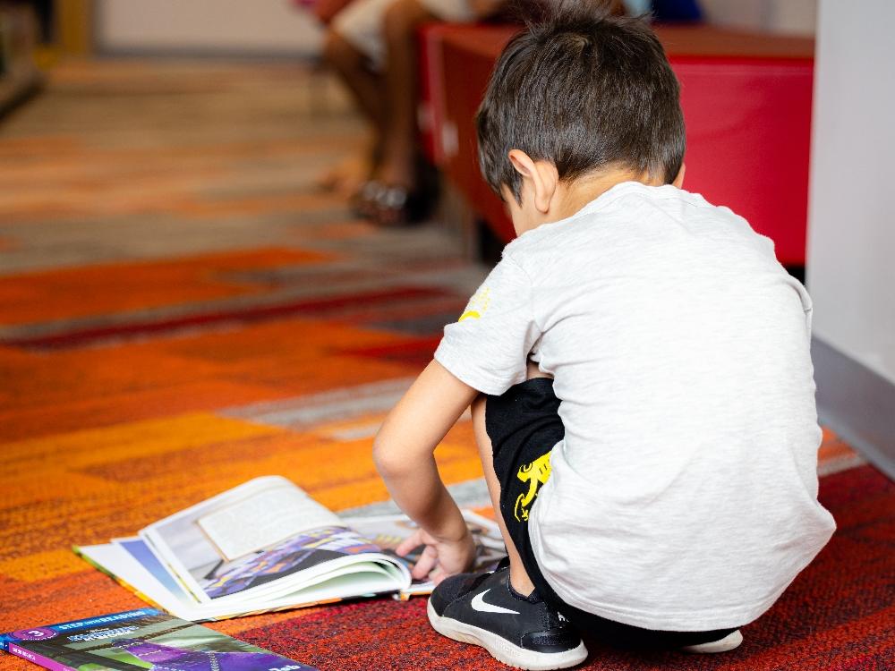 early childhood literacy Child reading books on colorful carpet
