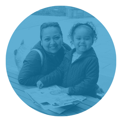 Smiling parent and child with open book outdoors.