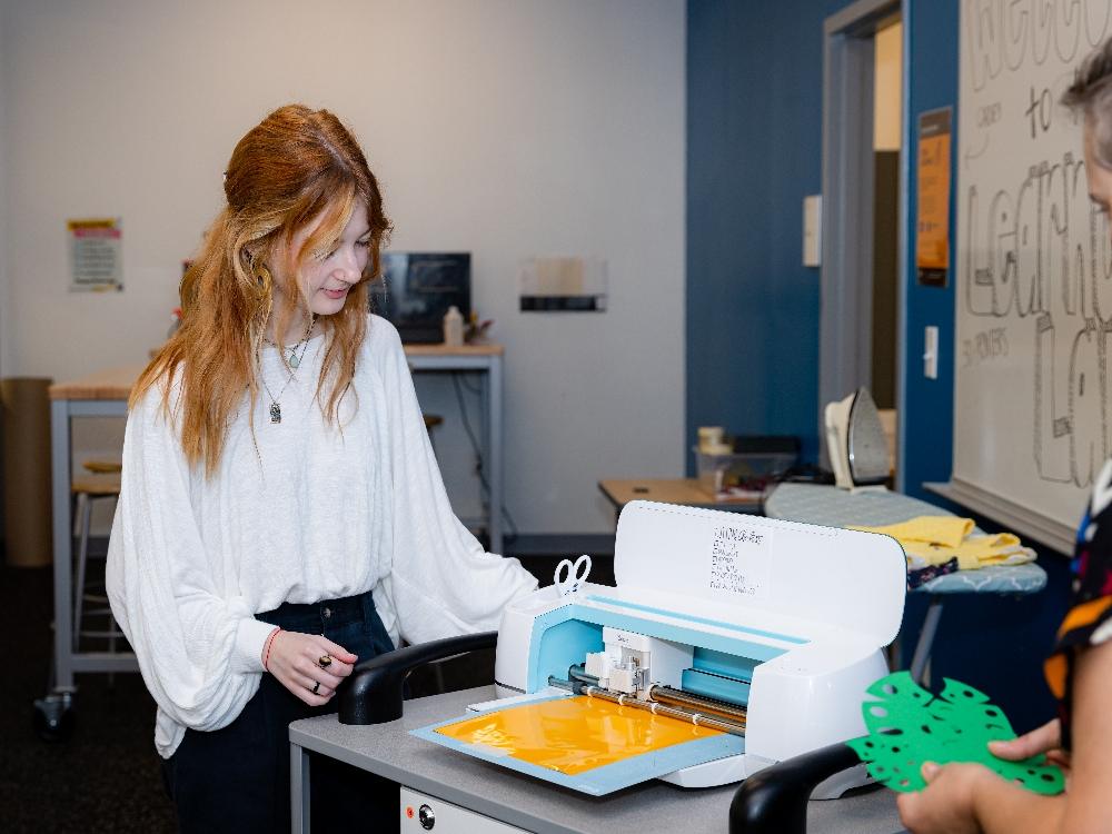 Person using cutting machine in creative workspace.
