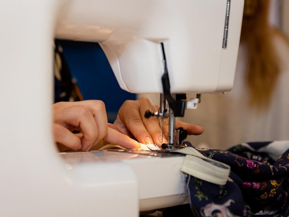 Person sewing fabric with sewing machine.