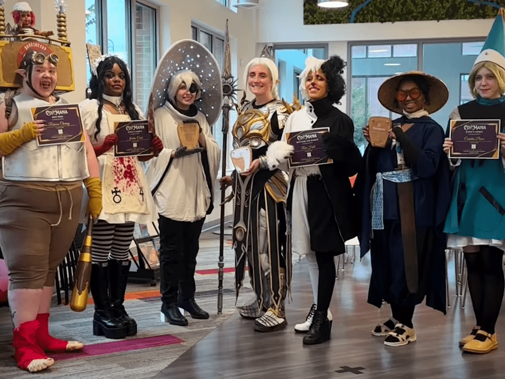 Cosplayers holding awards at a costume event.