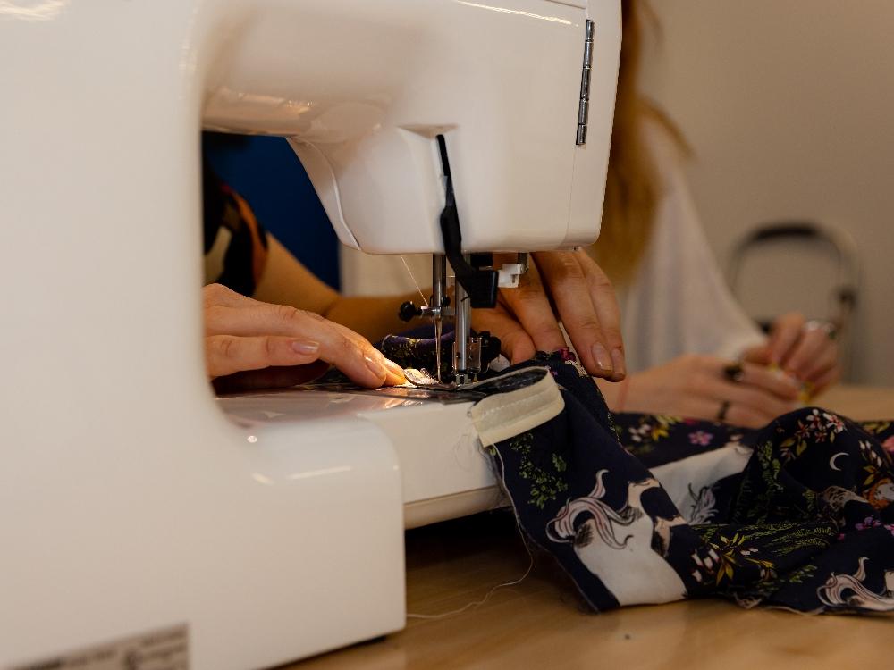Person sewing fabric on sewing machine