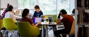 Students studying with laptops in library.