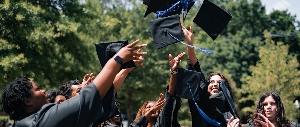 Graduates celebrating by tossing caps outdoors.