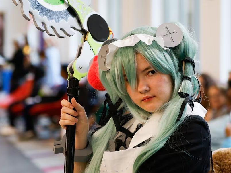 Person in cosplay with green wig and staff