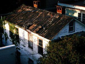 Old house with rusty roof and vines growing.