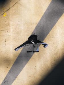 Gray and black hoodie on concrete with shadows.