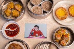 Dim sum dishes and baby photo on table.