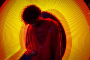 Person in red jacket with yellow light swirl