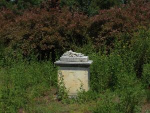 Stone pedestal with sculpture in garden