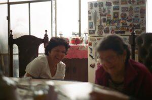 Two women laughing near decorated refrigerator.
