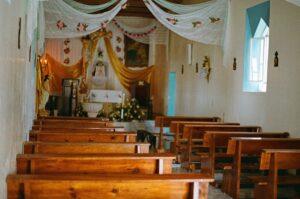 Interior of a decorated church with wooden pews.