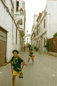 Kids playing in a narrow alleyway, cityscape view.