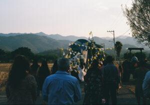 People walking in rural parade with tractor and decorations.