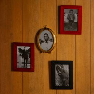 Four vintage portraits in colorful frames on wall.