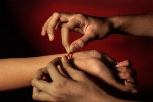 Hands tying red thread bracelet on wrist