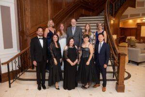 Ten formally dressed adults pose on an elegant staircase.