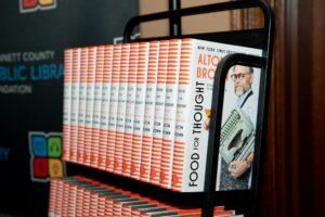 Rows of Alton Brown cookbooks on a black shelf