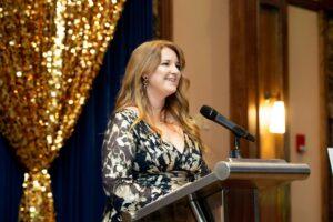 Woman speaking at podium during elegant indoor event