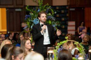 Man in tuxedo gives speech at floral banquet