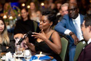 Woman speaks into microphone at elegant dinner event