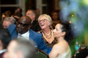 Smiling woman and guests seated at a crowded event