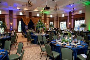 Elegant ballroom banquet with blue tables and gold backdrop