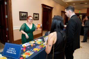 Woman presents early literacy programs at community event table.